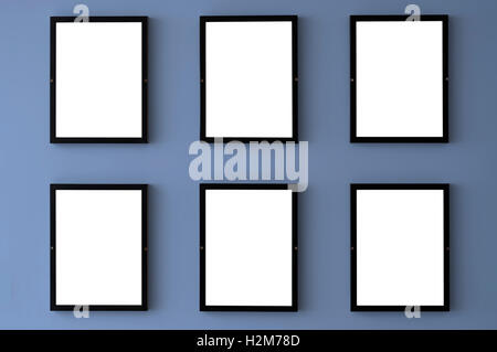 Six blank picture frames hang on a wall with the 2016 pantone color of serenity. Stock Photo