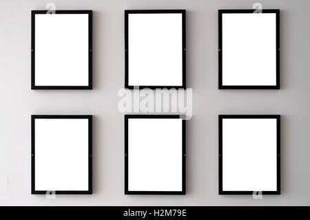 Six blank picture frames hanging on a white wall. Stock Photo