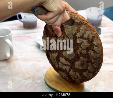 Baked bread being cut with a knife Stock Photo