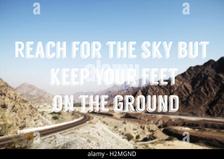 Photo of mountain road in UAE with text quote: Reach for the sky but keep your feet on the ground. Stock Photo