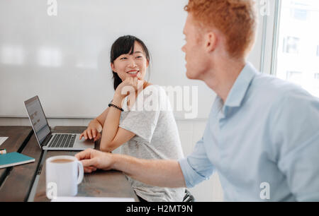 Two business people sitting at conference table and discussing during business meeting. Coworkers sitting in boardroom with lapt Stock Photo