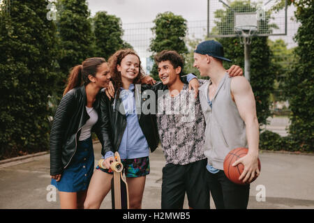 Portrait of four young friends standing together. Mixed race group of people having fun outdoors. Stock Photo