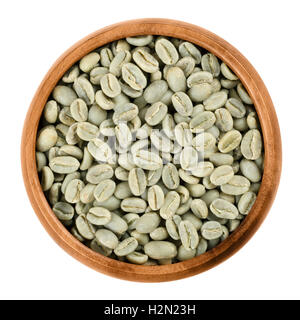 Green Arabica coffee beans in a wooden bowl on white background. Unroasted pits of the coffee cherries. Isolated close up macro. Stock Photo