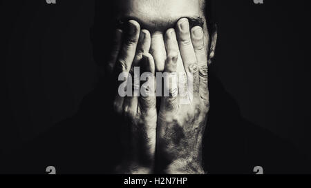 Portrait of a man with hands on face, depressed expression, in black and white. Stock Photo