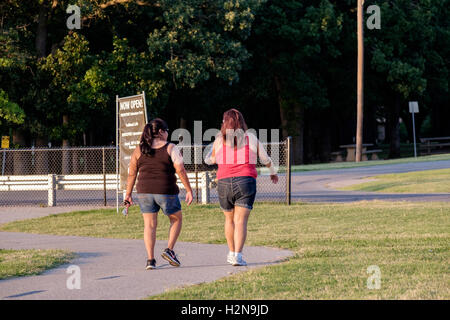 Two overweight ethnic young women walk for exercise in the Overholser lake trails in Oklahoma City, Oklahoma, USA. Stock Photo