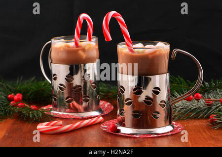 Cheery Christmas mugs of hot chocolate with mini marshmallows and peppermint candy canes on dark background with room for your t Stock Photo