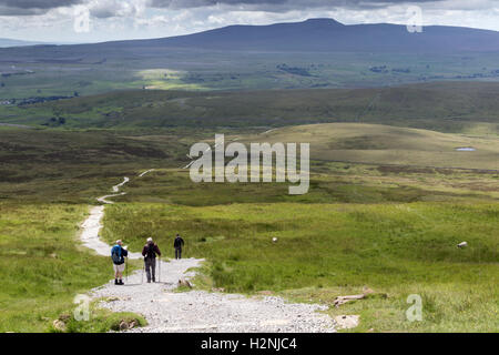 Walkers descend the Pennine Way path on Pen-y-ghent, with Ingleborough in the far distance Stock Photo