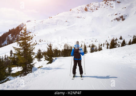 Skier skiing on easy blue trail with beautiful landscape in background Stock Photo