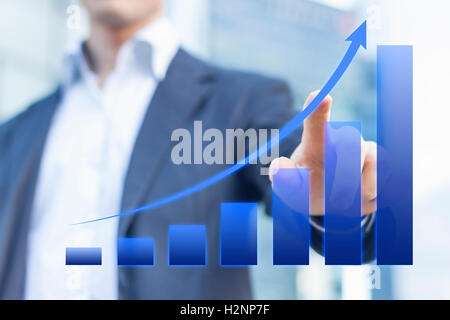 Business consultant presenting a blue chart about growing markets with office buildings in background Stock Photo