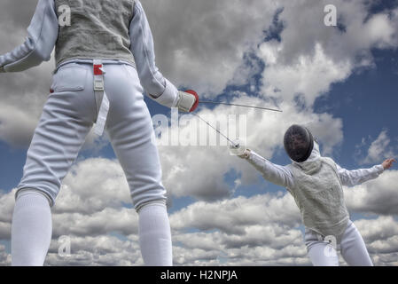 Fencing duel photo which is taken from lower perspective with dramatic clouds in the background. Stock Photo