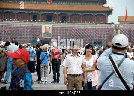 A proud Chinese couple poses in front of Chairman Mao's portrait at Tiananmen Square in Beijing, China. Stock Photo