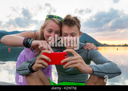 Young couple looking at mobile phone together, Schliersee, Upper Bavaria, Bavaria, Germany Stock Photo
