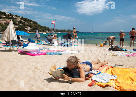 Woman lying on the beach reading a book, closeup, Le Lavandou area, Provence-Alpes-Côte d'Azur region, France Stock Photo