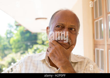 Closeup portrait, upset elderly pensioner, hands on face looking up thinking deeply, isolated outside outdoors background Stock Photo