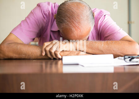 Closeup portrait, tired old bald boss sleeping after filling out so much paperwork, resting on desk, isolated indoors background Stock Photo