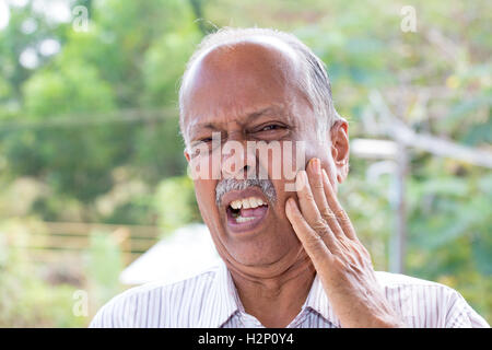 Closeup portrait elderly business man with tooth ache crown problem cavity grimacing from pain touching outside mouth with hand Stock Photo