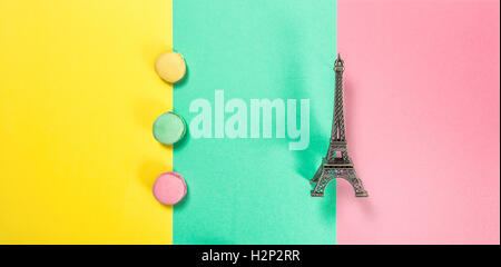 Macaron cookies on pink green yellow colored background. Macarons french cake. Eiffel tower Paris. Minimal concept Stock Photo
