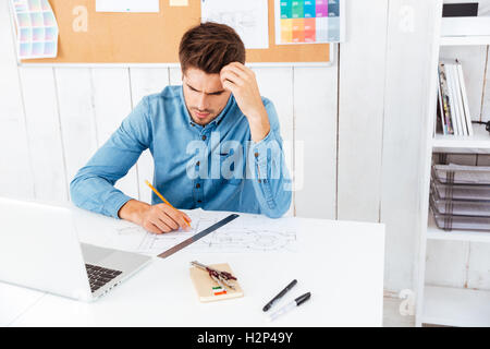 Serious smart businessman thinking about something using laptop in the office Stock Photo