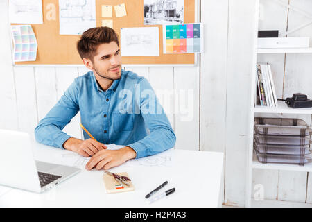 Handsome young smart businessman working with documents and computer in office Stock Photo