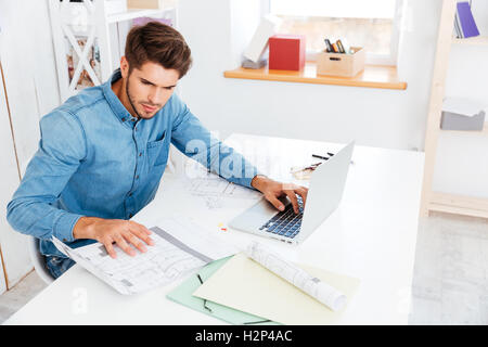 Handsome young smart businessman working with documents and computer in office Stock Photo