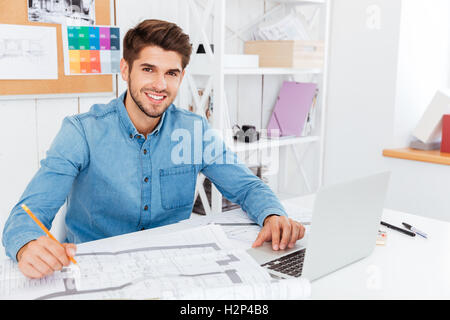 Handsome young businessman holding pencil and working with documents at the office Stock Photo