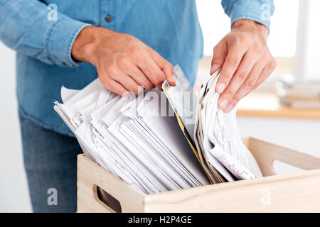 Close up portrait of man hands looking for documents in stack of folders on the office table Stock Photo