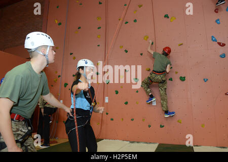 A climber makes process up a climbing wall to achieve his goal of reaching the top. Stock Photo