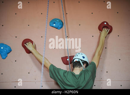 STOCK IMAGE A climber makes process up a climbing wall to achieve his goal of reaching the top. Stock Photo