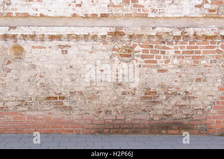 Broken old bricklaying wall from red white bricks with damaged plaster and road pavement background texture Stock Photo