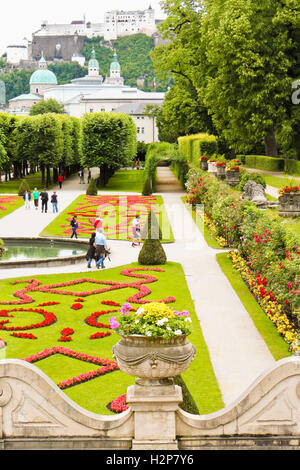 Salzburg, Austria - July 4, 2013: Visitors are walking in beautiful Mirabell Gardens, a castle Hohensalzburg, on the background. Stock Photo