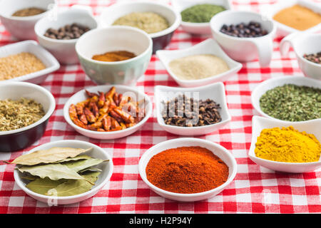 Various dried herbs and spices on checkered tablecloth. Stock Photo