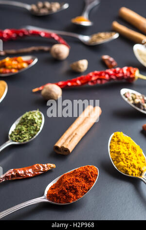 Various spices in spoons on black background. Stock Photo