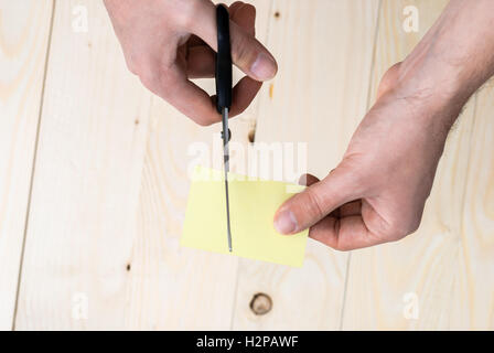 hand is cutting a sheet of yellow paper Stock Photo