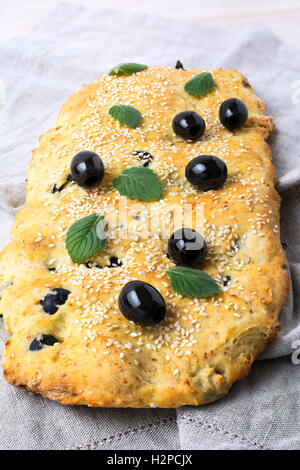 Italian bread with olive, garlic and herbs. Homemade traditional Italian bread focaccia on the linen napkin. Stock Photo