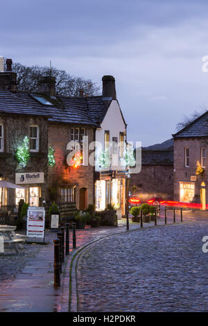 Both Christmas and trail lights add colour on a dark winter night - Grassington Village, Yorkshire Dales National Park, England. Stock Photo