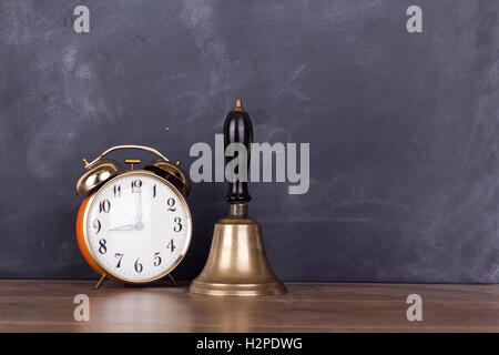 Old bell and alarm clock against a blackboard Stock Photo