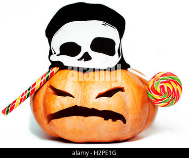 halloween holiday traditional scary smiling orange pumpkin in black skull hat and candys isolated on white background close up Stock Photo