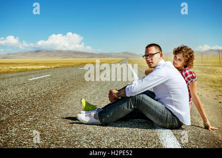 Love couple sits on the road in the mountains Stock Photo