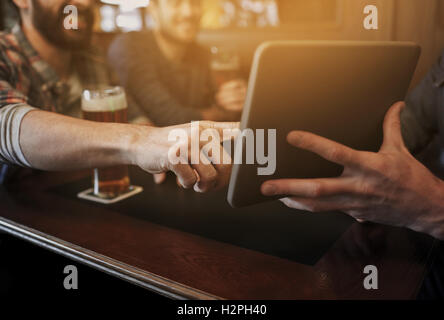 close up of men with tablet pc and beer at bar Stock Photo