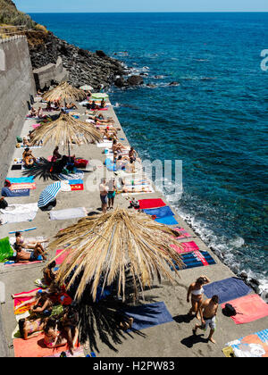 People enjoy the summer weather going swimming in the atlantic ocean at the rocky beach of Jardim do Mar Stock Photo