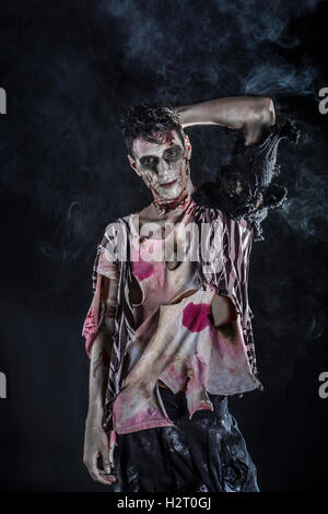 Male zombie standing on black background, looking at camera. Halloween theme Stock Photo