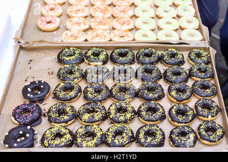 Chocolate donuts, yellow, red, orange, pink and green sugar on top, shallow focus Stock Photo