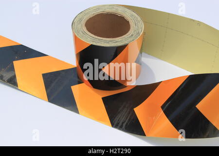 A large roll of yellow and black hazard tape on a white background Stock Photo