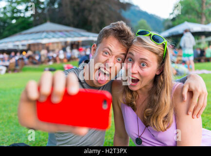 Young man and young woman making faces, taking photo with mobile phone, selfie, Bavaria, Germany Stock Photo