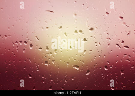 Rain water drops on glass window. Beautiful background of rain drops on glass at the sunset Stock Photo