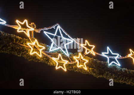 chain of bright christmas stars on dark background Stock Photo