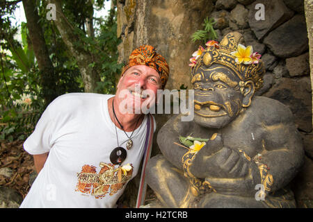 Indonesia, Bali, Tengannan, Bali Aga village, tourist wearing Udeng Head cloth, and Hindu deity carving Stock Photo