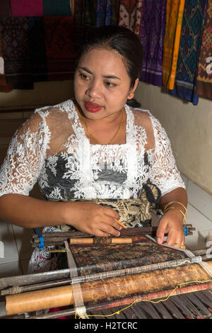 Indonesia, Bali, Tengannan, traditional textile production, woman hand weaving double ikat fabric on backstrap loom Stock Photo