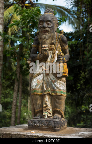 Indonesia, Bali, Tengannan, Bali Aga village, statue of Hindu holy man, with Buddhist bell and lotus flower Stock Photo