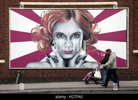 Pedestrian walking past street art, graffiti wall painting, decoration, at the Sun, Spray and Art Festival Art in East Topping street, Blackpool, Lancashire, UK Stock Photo